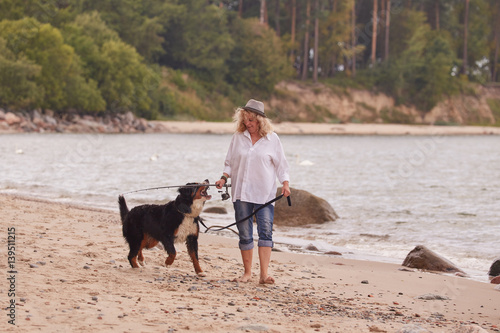 woman with her dog on sea beach walking
