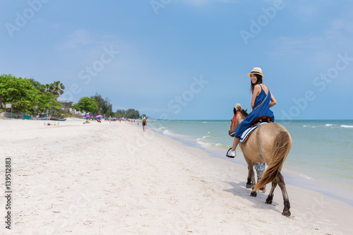 Woman riding horse on sand beach