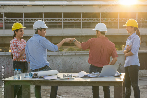 Fist Bumping Corporate Colleagues Teamwork between professional construction engineers after project complete at the sunset time  Industrial engineering and teamworks Concept  worm color tone