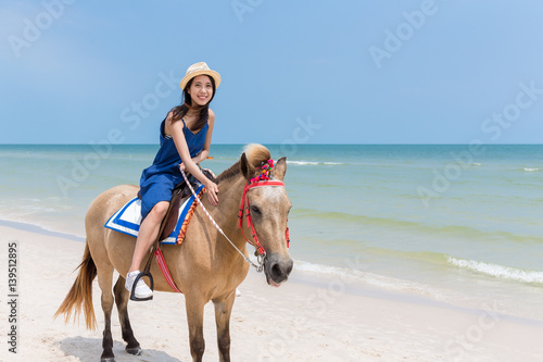 Woman riding horse on beautiful sand beach © leungchopan