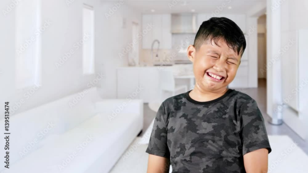 Little boy standing in the living room while crying and wiping his tears, shot at home Little boy standing in the living room while crying and wiping his tears, shot at home