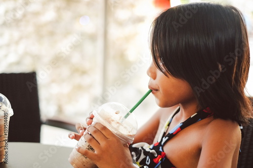 Cute little girl drinking ice cold chocolate shake