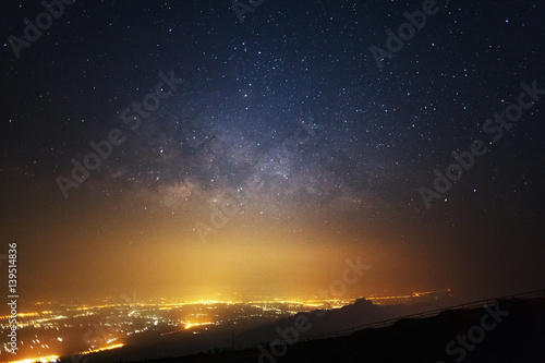 Milky way galaxy and city light at Phutabberk Phetchabun in Thailand.Long exposure photograph.With grain
