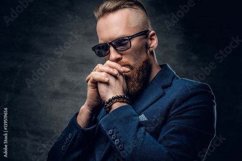 Redhead male dressed in a blue suit and sunglasses.