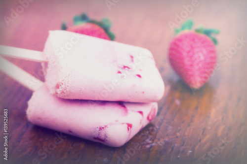 Homemade strawberry ice lolly on rustic background