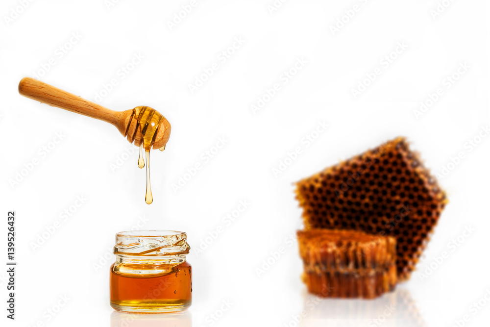 Drop of brown honey on a wooden spoon and brown Honeycomb on a white background Drop of brown honey on a wooden spoon and brown Honeycomb on a white background