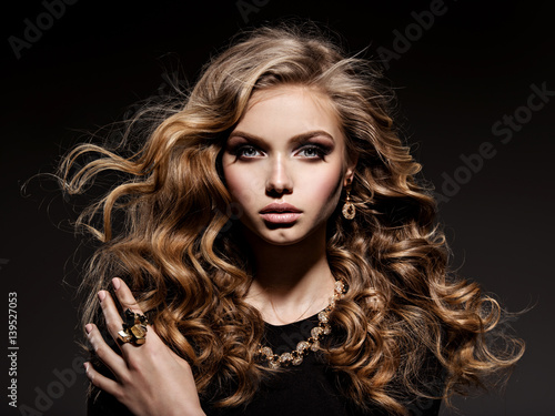 Beautiful woman with long curly hair and gold jewelry