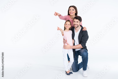 Happy young family standing together and pointing with fingers on white