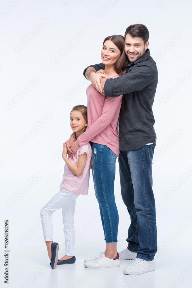 Happy family with one child standing together and hugging on white Happy family with one child standing together and hugging on white