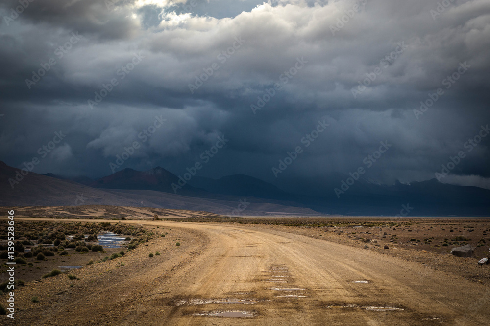 Landscape with dirt road in the mountains under stormy sky.Rural mountain road in Peru, South America, just before the snow storm. Mountains in the background.