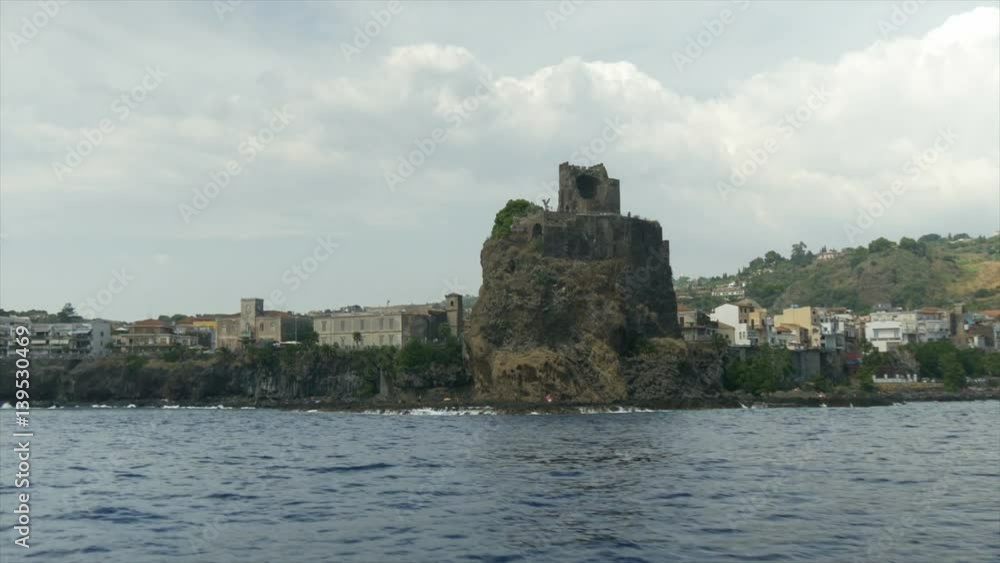 The Aci Castello's castle on a ridge of lava, built by the Normans from black lava stone, in the mediterranean sea of Sicily (Italy).