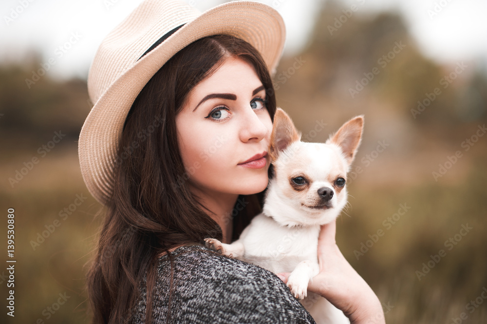 Beautiful girl 20-24 year old holding chihuahua puppy outdoors. Looking at camera. Beautiful girl 20-24 year old holding chihuahua puppy outdoors. Looking at camera.