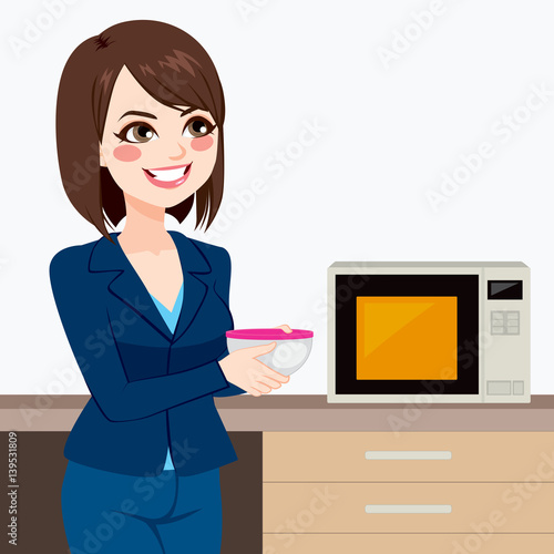 Beautiful brunette businesswoman using microwave to heat homemade food on business office kitchen