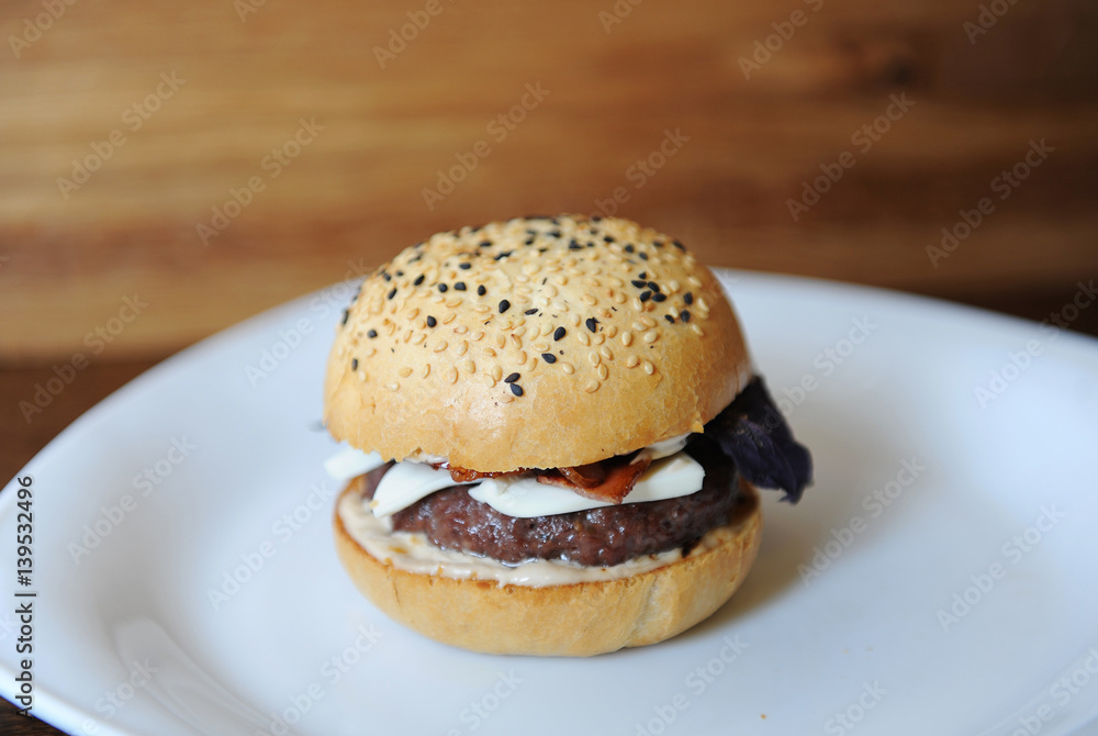 Burger on a white plate. Wooden background
