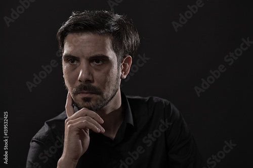 Portrait of pensive adult man on black background.