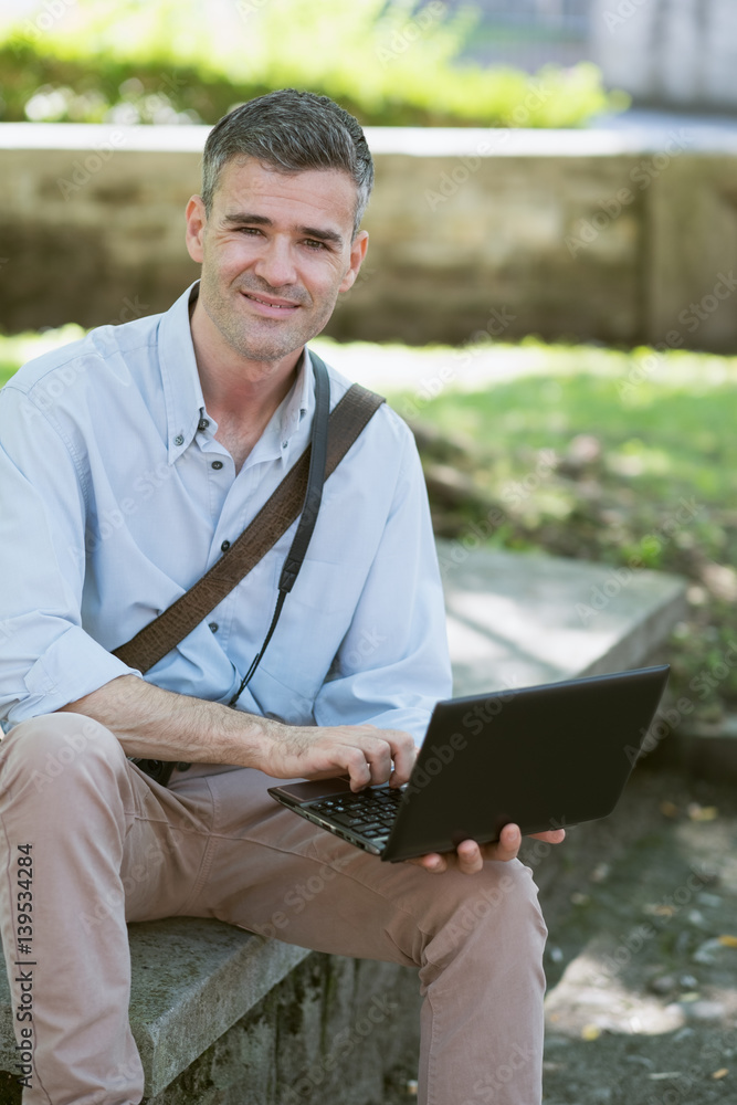Fototapeta premium Man using a laptop outdoors