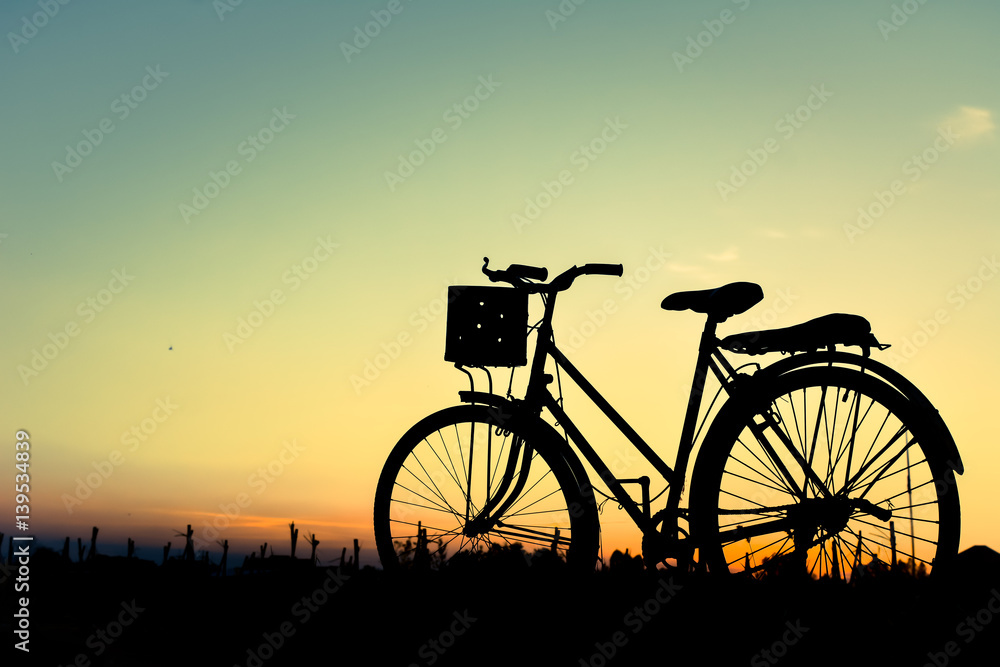 Silhouette of old bicycle on grass with the sky sunset, color of vintage tone and soft focus concept journey Silhouette of old bicycle on grass with the sky sunset, color of vintage tone and soft focus concept journey