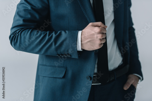 Mid section of businessman in stylish suit posing on grey