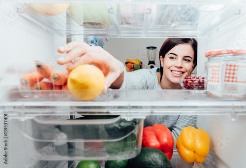 Woman taking a lemon out of the fridge photo