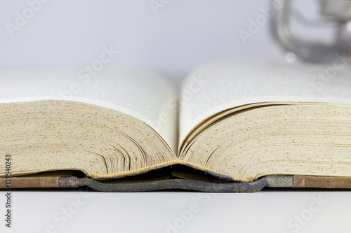Closeup image of an opened old book on a grey table.