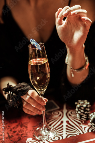 partial view of woman holding drink with poker chip in casino