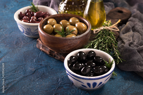 bowls with different kind of olives green olives, black olives, kalamata olives on table