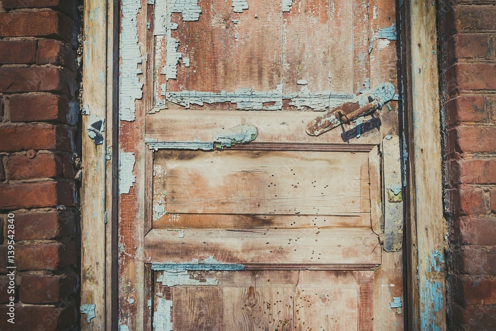 Naklejka premium Old abandoned door, detail of a door of a house in ruins. Stock image.