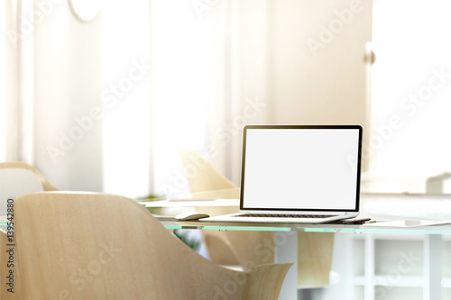 Blank laptop screen mockup in office  depth of field effect  3d rendering. Modern portable computer display mock up  glass desk  wooden chairs. Coworking work room with empty pc monitor