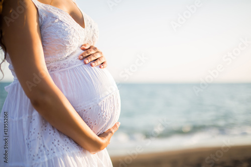Young pregnant woman walking on the beach  photo