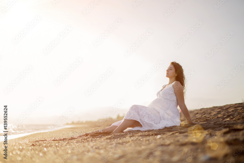 Young pregnant woman walking on the beach 