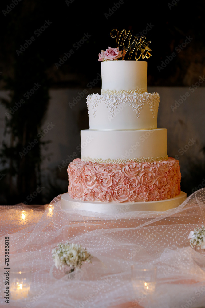 Torta nuziale bianca e rosa con scritto mr & mrs, sopra tavolo con candele  Stock Photo | Adobe Stock