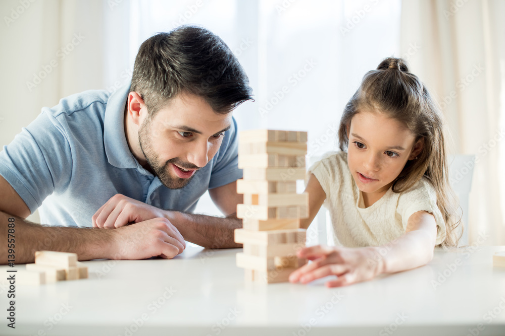 portrait of focused daughter playing jenga game with father at home portrait of focused daughter playing jenga game with father at home