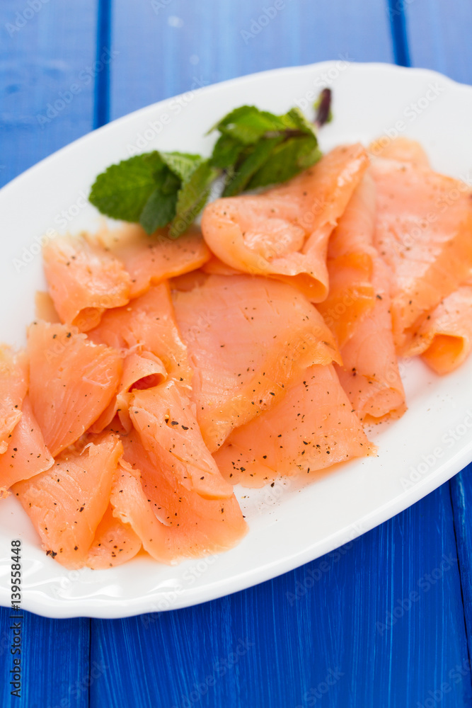 smoked salmon on white plate on wooden background