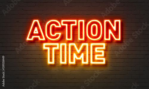 Action time neon sign on brick wall background.