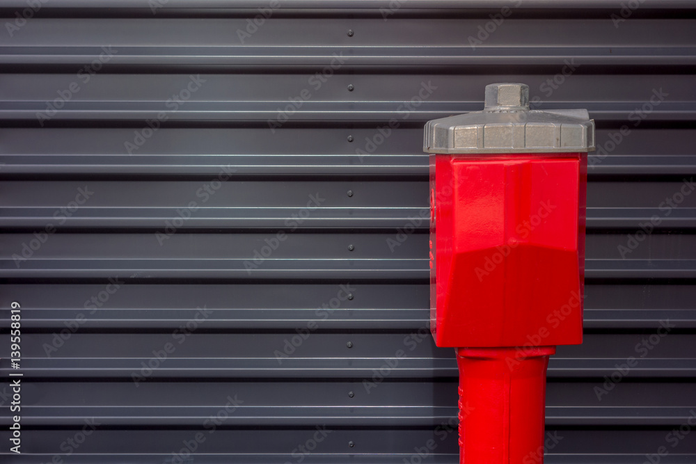 Roter Hydrant vor grauer Wellblechwand
