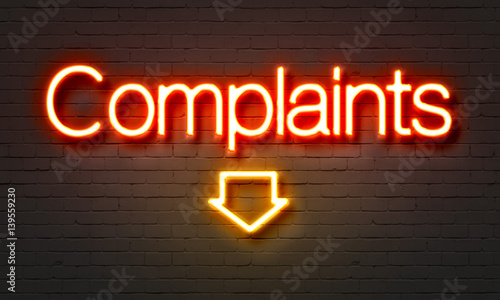 Complaints neon sign on brick wall background.