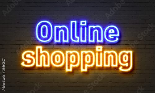 Online shopping neon sign on brick wall background.