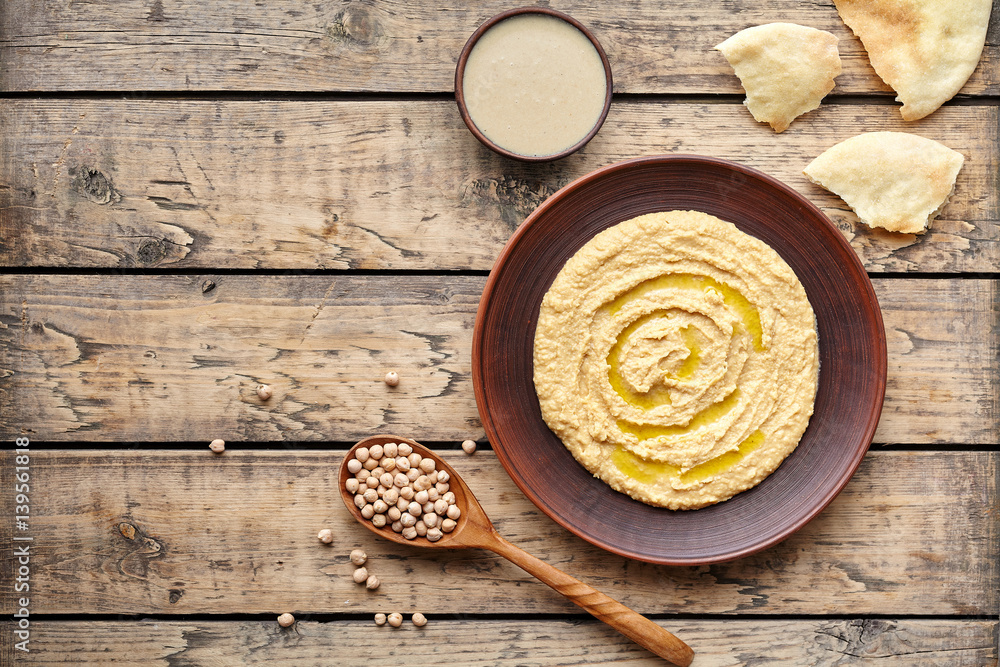Hummus eastern traditional Israel snack chickpea vegan natural nutrition lunch dip paste with pita bread tahini and olive oil in clay plate on rustic flat lay. Healthy dietary fiber protein food Hummus eastern traditional Israel snack chickpea vegan natural nutrition lunch dip paste with pita bread tahini and olive oil in clay plate on rustic flat lay. Healthy dietary fiber protein food