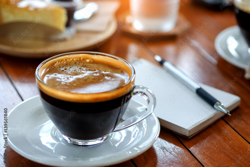 Coffee cup with blurred behind pen on notebook. Coffee cup with blurred behind pen on notebook.