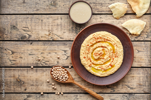 Hummus eastern homemade snack chickpea vegan natural nutrition lunch dip paste with pita bread paprika tahini and olive oil in clay plate on rustic flat lay. Healthy dietary fiber protein food