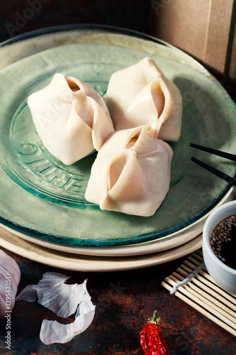 Uzbek dumplings (manti) with sauce and black chopsticks on glass plate