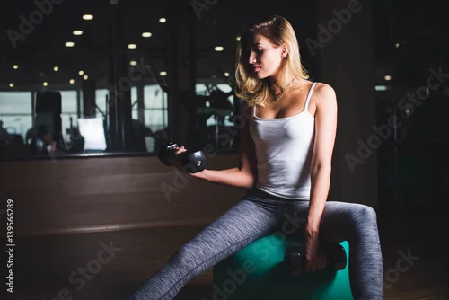 Obraz Dziewczyna robi ćwiczeniom z dumbbell w gym