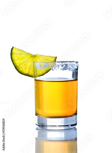 Shot of golden tequila with lime on a white background for isolation