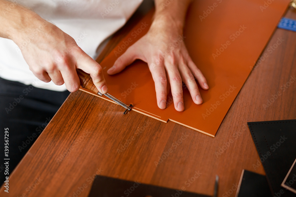 Obraz premium Man using special knife or cutter while processing leather workpiece