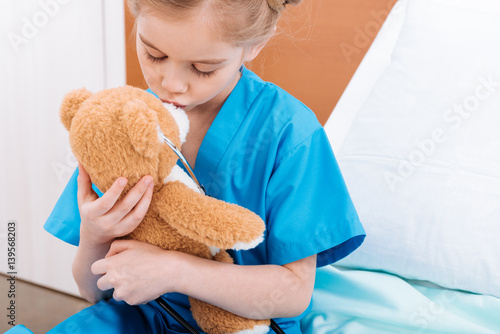 portrait of girl nurse kissing teddy bear in hospital chamber