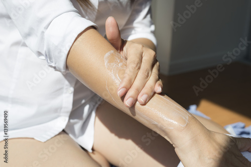 Beauty series: Asian woman applying lotion to her arms, closeup