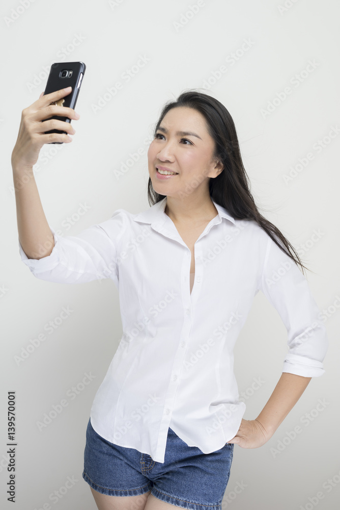 Technology series: Asian woman taking selfie against white background Technology series: Asian woman taking selfie against white background