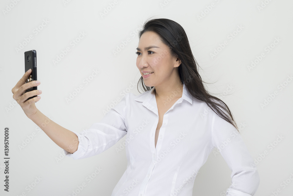 Technology series: Asian woman taking selfie against white background Technology series: Asian woman taking selfie against white background