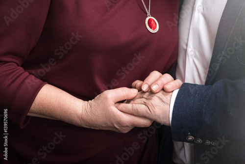 Close-up partial view of senior couple holding hands