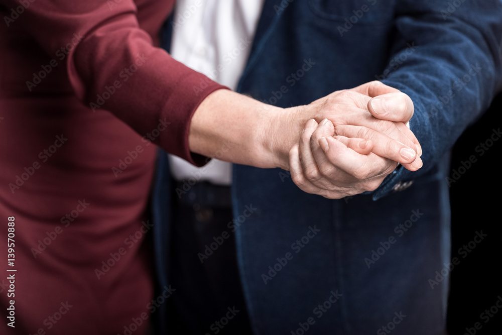 Fototapeta premium Close-up partial view of senior couple holding hands while dancing